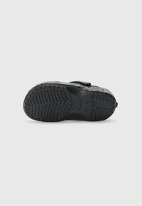 Black rubber shoe sole with deep grooves and treads. Features embossed logo and brand markings. Smooth texture with reinforced heel area.