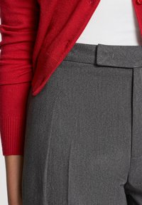 Pantaloni grigi su misura con una texture liscia, dotati di una parte frontale piatta e una vita slim, abbinati a un cardigan rosso vivace.