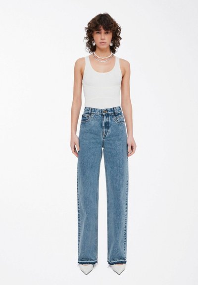 Top sin mangas de canalé en gris claro combinado con jeans rectos de talle alto en azul claro, con dobladillos desflecados y un diseño clásico de cinco bolsillos.