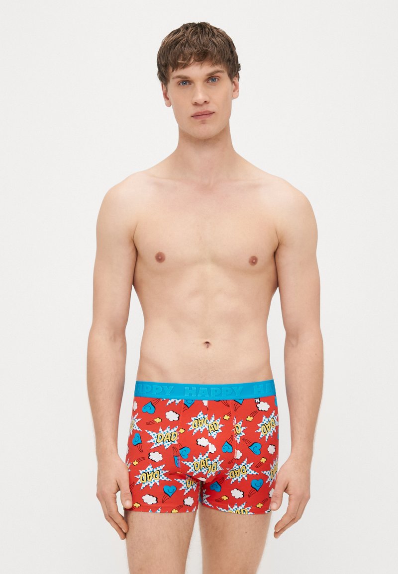 Sarkani bokseršorti ar zilu elastīgu jostu, rotāti ar krāsainiem komiksu stila attēliem, tostarp sirdīm un vārdu "TĒTIS".