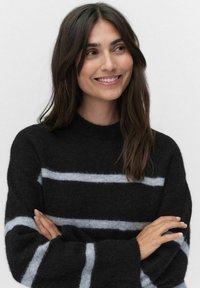 Svart tröja med ljusgrå horisontella ränder, tillverkad av mjukt, texturerat tyg. Har rund nacke och löst sittande ärmar.