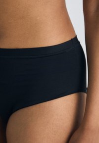 Bas de bikini noir taille haute avec une texture lisse et un design minimaliste. Doté d'une large ceinture et sans motifs ni accents visibles.