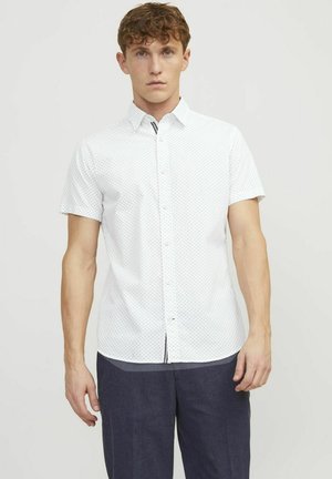 Camicia bianca a maniche corte, con un motivo a pois, realizzata in tessuto leggero. Presenta un colletto classico e una vestibilità dritta.