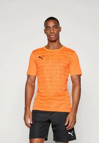 Cămașă sport cu mânecă scurtă Puma, de culoare portocalie aprinsă, având un model texturat, guler rotund și un mic logo negru pe pieptul stâng.