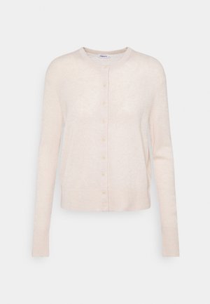 Henkilö, jolla on musta kaksirivinen bleiseri, mustat halkiolla varustetut housut, beige toppi ja mustat tupsuloaferit, pitelee tummanpuhuvaa kirjekuorilaukkua.