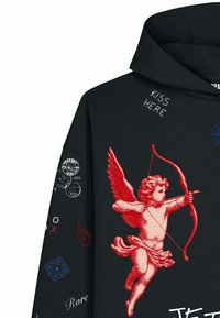 Sweat à capuche noir avec un chérubin rouge visant un arc et une flèche, texte "KISS HERE" près du col, et divers petits détails graphiques blancs, rouges et bleus sur la manche.