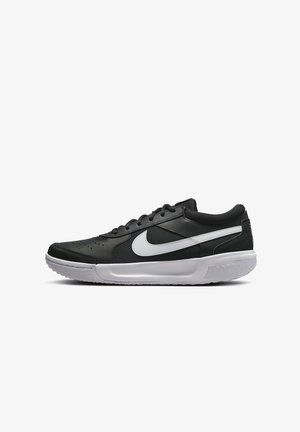 Baskets basses noires Nike avec logo swoosh blanc, semelle épaisse blanche et lacets noirs sur fond blanc uni.