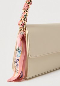Sac à main beige texturé avec un détail d'écharpe imprimée de fleurs roses sur la anse en chaîne dorée. Dispose d'une fermeture à rabat et de lignes épurées.