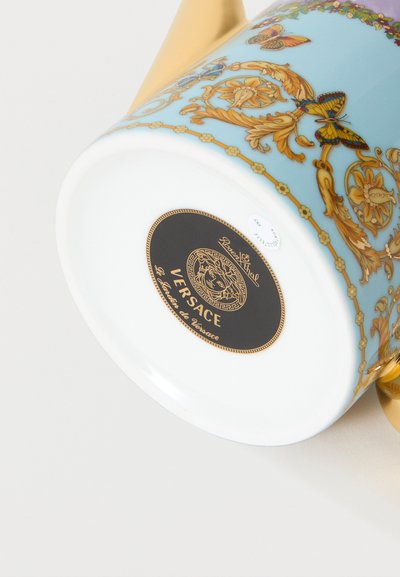 Λευκό και μπλε πορσελάνινο φλιτζάνι με χρυσή λαβή, διακοσμημένο με χρυσά σχέδια, λουλούδια και πεταλούδες, με τα λογότυπα Versace και Rosenthal στο κάτω μέρος.