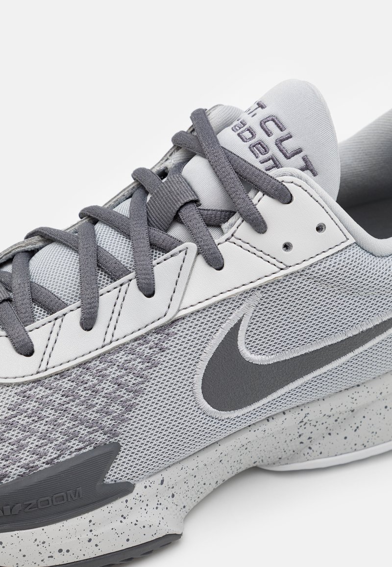 Baskets Nike avec une tige en mesh gris, des lacets gris et une semelle intermédiaire blanche avec un motif moucheté. Marquage notable sur la languette et sur le côté.