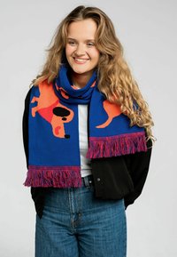 Niebieski szal z wesołym wzorem pomarańczowego psa, z teksturowanym frędzlem w kolorze różowym i czerwonym na końcach. Miękka, dziana tkanina.
