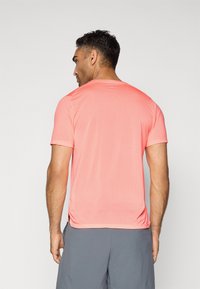 Kurzärmliges Sportshirt in lebhaftem Korallenrot, ausgestattet mit einem strukturierten Mesh-Stoff, Rundhalsausschnitt und genähten Seitennähten.
