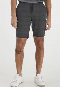 Gray patterned shorts made of lightweight fabric, featuring an elastic waistband with a drawstring and side pockets. Paired with white sneakers.