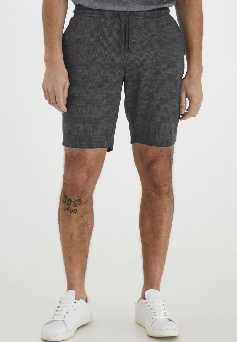 Gray patterned shorts made of lightweight fabric, featuring an elastic waistband with a drawstring and side pockets. Paired with white sneakers.