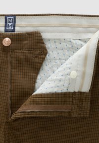 Bruine geruite broek met een ritssluiting en knoop, en een witte voering met blauwe stippen.