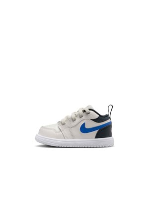 Hvid børne-sneaker med blå Nike-swoosh, sort hæl og hvid sål, vist i sideprofil på hvid baggrund.