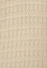 Cremfarbene Strickware mit einem erhabenen, strukturierten Muster. Die Maschen bilden ein gitterartiges Design und zeigen weiches, dickes Garn.