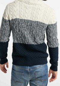 Suéter de punto con un diseño de bloques de color en crema, gris y marino, con trenzado texturizado y puños y dobladillo acanalados.