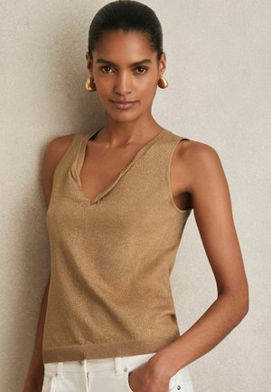 Light gold sleeveless sweater with a V-neck, ribbed hem, and a subtle shimmer. Smooth fabric texture, designed for a fitted silhouette.