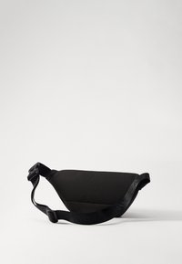 Černá tkaninová taška na rameno s elegantním trojúhelníkovým tvarem a nastavitelným popruhem se vzorovaným logem. Hladká textura, minimalistický design.