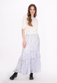 Hvid kortærmet sweater parret med en luftig, lys lilla blomster maxi-nederdel med flæser og sorte snørebåndsstøvler.
