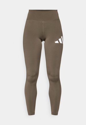 Leggings castanhas de cintura alta com uma textura suave, apresentando um logo branco da Adidas na coxa esquerda e um design até ao tornozelo.