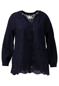 Blouse à manches longues bleu marine avec décolleté en V, ornée de broderies florales et d'un ourlet festonné avec des découpes. Fermeture par boutons à l'avant.