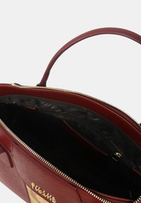 Borsa a tracolla in pelle rossa con chiusura a zip, caratterizzata da una superficie liscia, una forma strutturata e un dettaglio del logo metallico sulla parte anteriore.