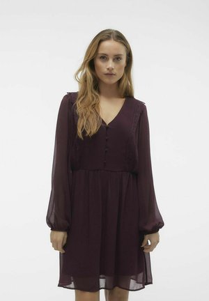 Robe bordeaux en tissu léger, avec de longues manches bouffantes, uncol en V, des boutons et une finition en dentelle le long du corsage.