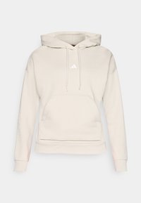 Lichtbeige hoodie van zacht materiaal, met een frontale kangoeroezak, trekkoordcapuchon en een klein wit logo op de borst.