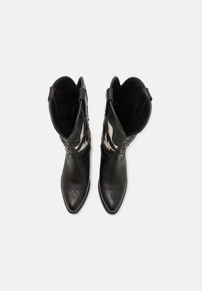 Paar schwarze Leder-Cowboystiefel mit weißen, gestickten Flammenmustern, spitzen Zehen und Zuglaschen auf einfachem hellem Hintergrund.