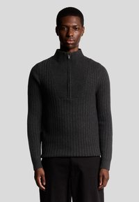 Donkergrijze geribbelde trui met een hoge kraag en een kwart ritssluiting. Heeft een gestructureerd patroon en een aansluitend ontwerp. Gemaakt van gebreid materiaal.