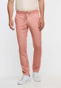 Lätta, laxfärgade chinos med dragsko i midjan och smalnande ben, kombinerat med vita sneakers. Texturerat tyg, avslappnad design.