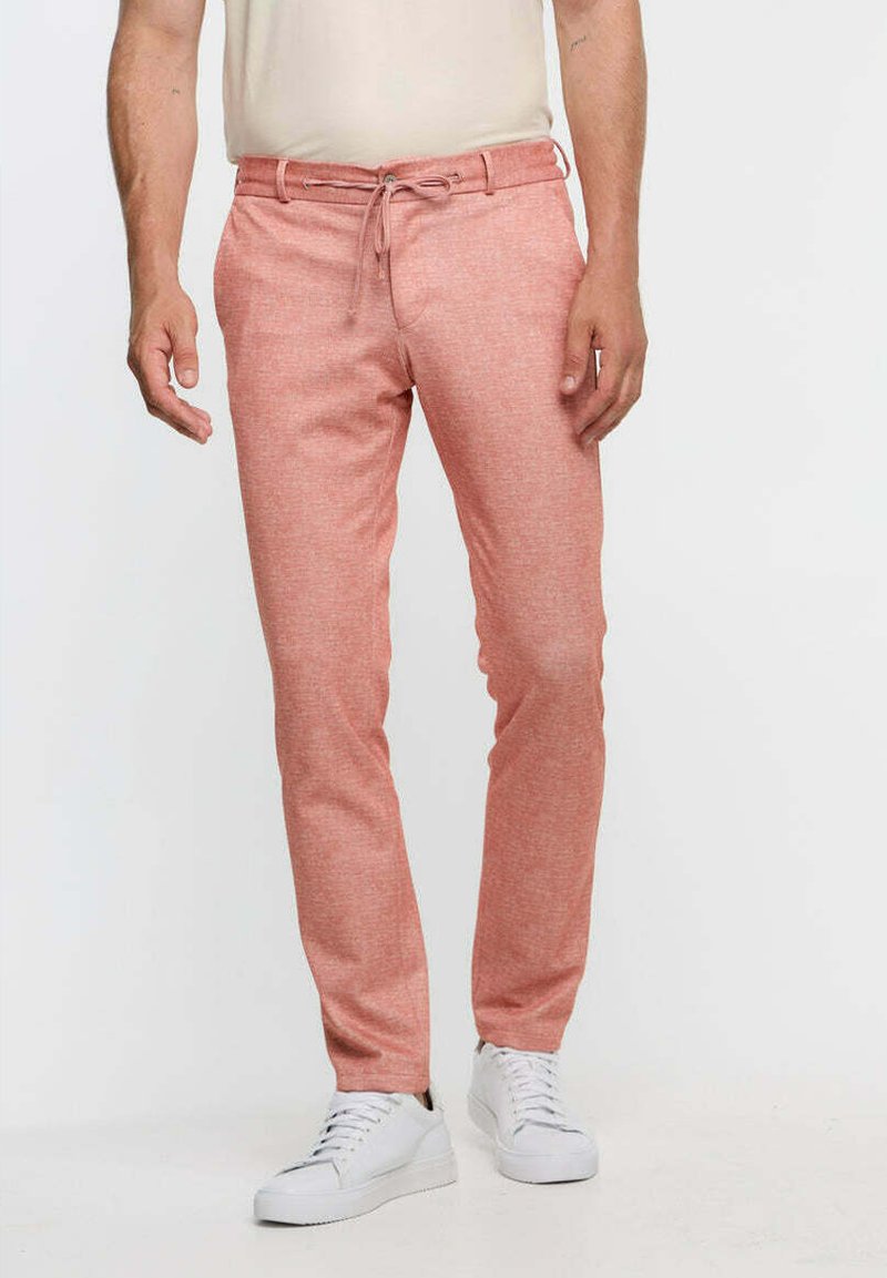 Lightweight, salmon-colored chinos with a drawstring waist and tapered legs, paired with white sneakers. Textured fabric, casual design.