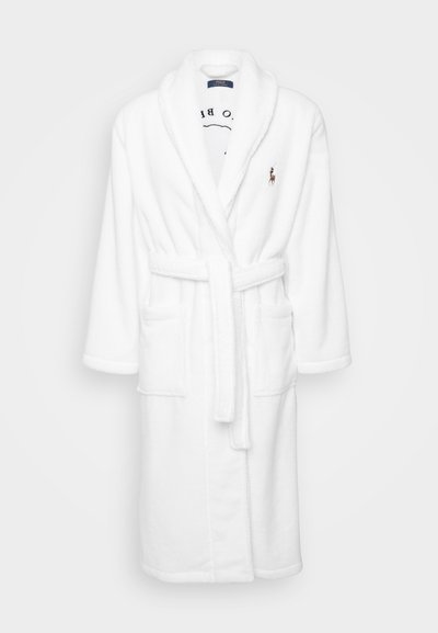 Hvit badekåpe i myk, plysj stoff; har sjalskrage, knytebelte, to frontlommer og et brodert logo på brystet.