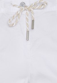 Witte broek met een gevlochten touwkoord met zilverkleurige metalen uiteinden, subtiele textuur en een knoopsluiting met reliëfdetail.