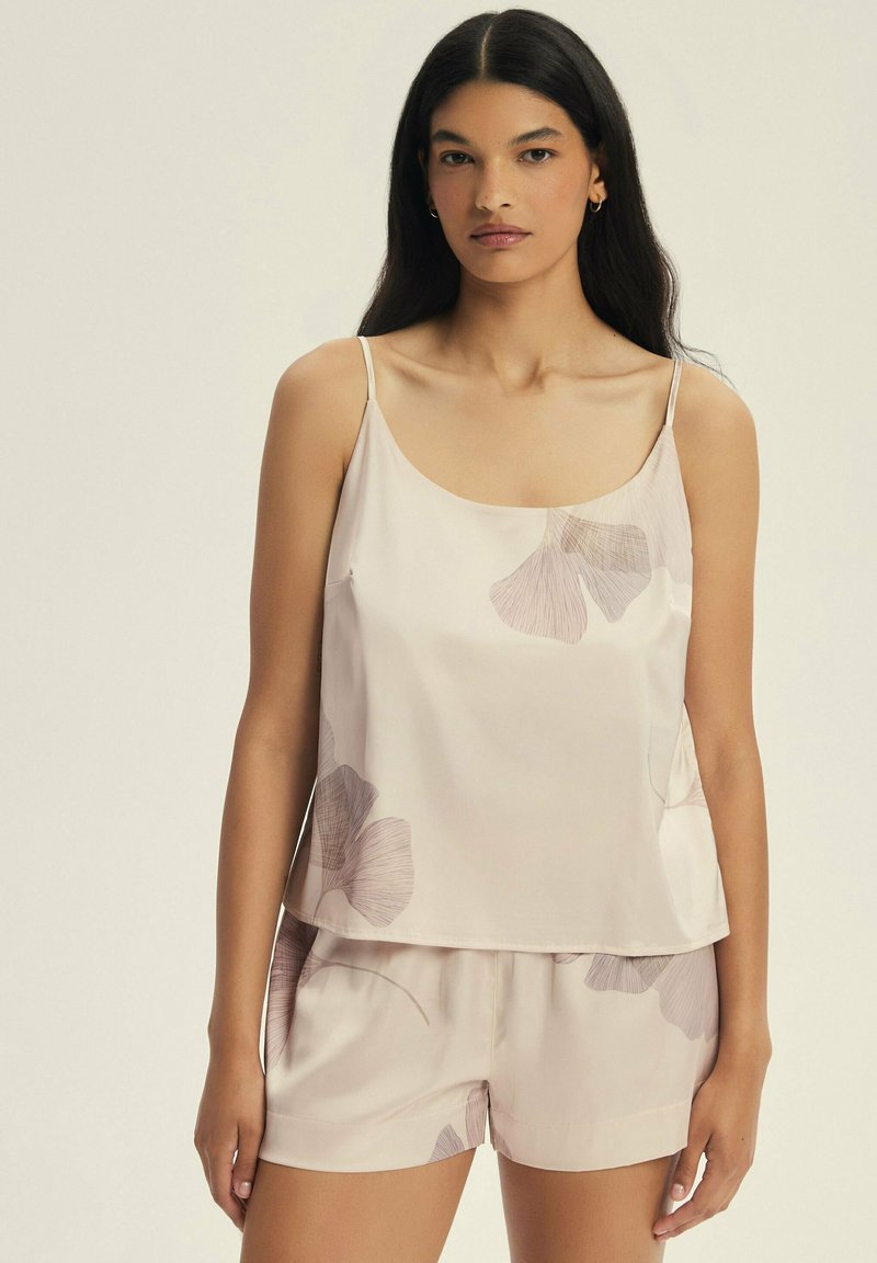 Jasnoróżowy zestaw topu na ramiączkach i szortów wykonany z gładkiego materiału, z delikatnymi kwiatowymi wzorami w ciemniejszym różu i beżowych odcieniach.