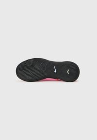 Nike-sko såle med en svart gummioverflate med fiskebensmønster, rosa detaljer og en liten blå logo. Teksturert for grep.
