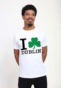White cotton t-shirt featuring black text "I" and "DUBLIN," with a green shamrock graphic in the center. Simple, casual design.