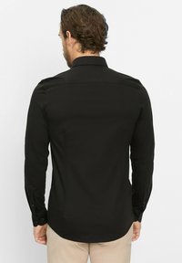 Zwarte lange mouwen shirt met een gladde textuur, voorzien van een puntige kraag en knoopmanchetten, ontworpen met een getailleerde pasvorm.