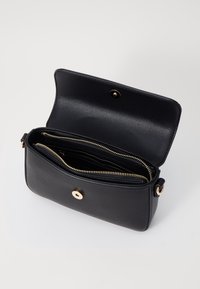 Borsa a tracolla in pelle nera con finitura texture, dotata di chiusura a scatto dorata e due scomparti con zip all'interno.