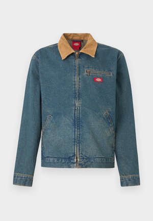 Chaqueta vaquera con cuello de pana marrón, cremallera frontal, bolsillo en el pecho y bolsillos laterales. Color azul claro con secciones descoloridas y detalles cosidos.