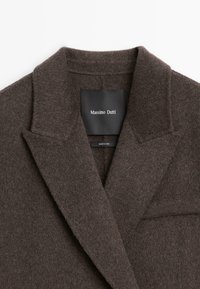Blazer en mélange de laine marron avec un col cranté, des épaules structurées et une surface douce et texturée. Étiquette Massimo Dutti visible.