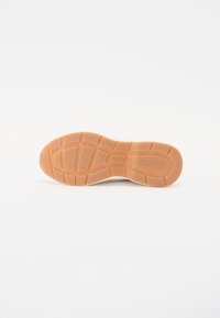 Semelle d'une chaussure de couleur havane avec motifs antidérapants texturés et le nom de la marque "KLDQ" embossé près du talon.