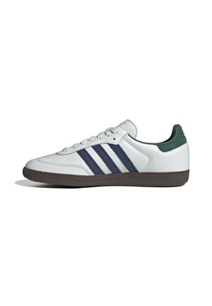 Hvid sneaker med mørkeblå striber, grøn hælkappe, hvide snørebånd og brun tekstureret sål, vist fra venstre side på hvid baggrund.