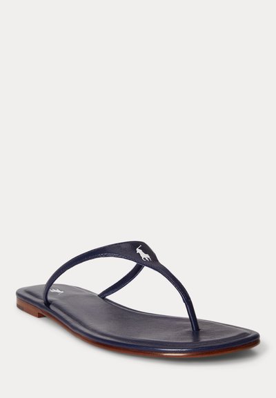 Σανδάλι τύπου φλιπ-φλοπ από δέρμα σε ναυτικό μπλε χρώμα με λεπτές λουράκια, επίπεδη καφέ σόλα και λευκό λογότυπο παίκτη πόλο στο λουράκι και στη σόλα του ποδιού.