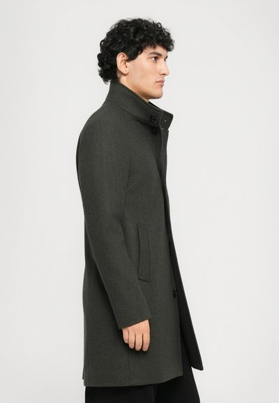 Manteau en laine grise avec un col haut, design à boutonnage simple, et deux poches latérales, comportant des boutons noirs et une texture lisse.