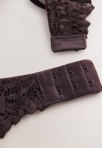 Agrafe de soutien-gorge en dentelle violet foncé avec trois crochets et œillets sur fond blanc.