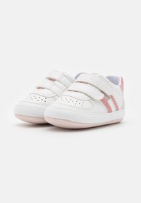 Bílé tenisky pro batolata s růžovými pruhovanými detaily, suchým zipem, perforovanými prvky a designem se zaoblenou špičkou.