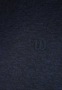 Camiseta atlética azul marino hecha de tela texturizada, con un logo de goma negra en el pecho. Diseño sencillo sin patrones ni acentos.